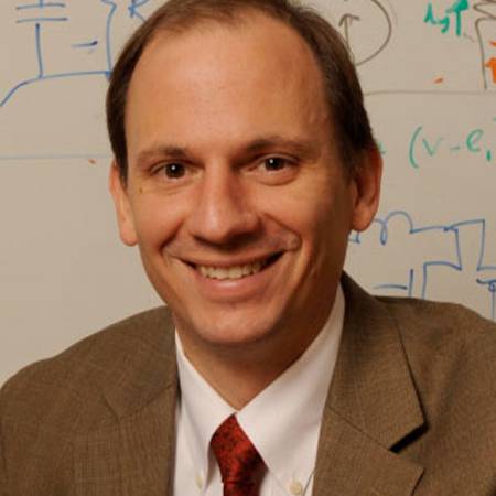photo of David Perreault seated in front of whiteboard with mathematical figures