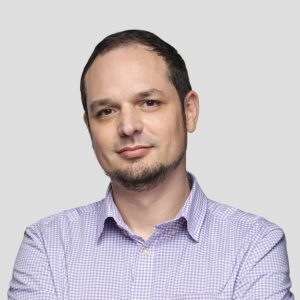 john rozen in grid pattern collared shirt in front of light gray background