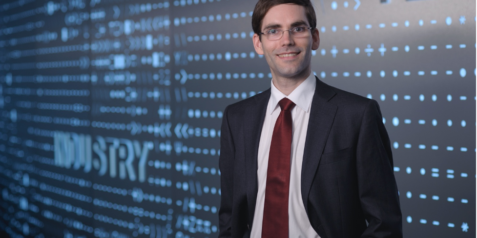 tomas palacios standing in front of blue wall with pattern of numerical symbols