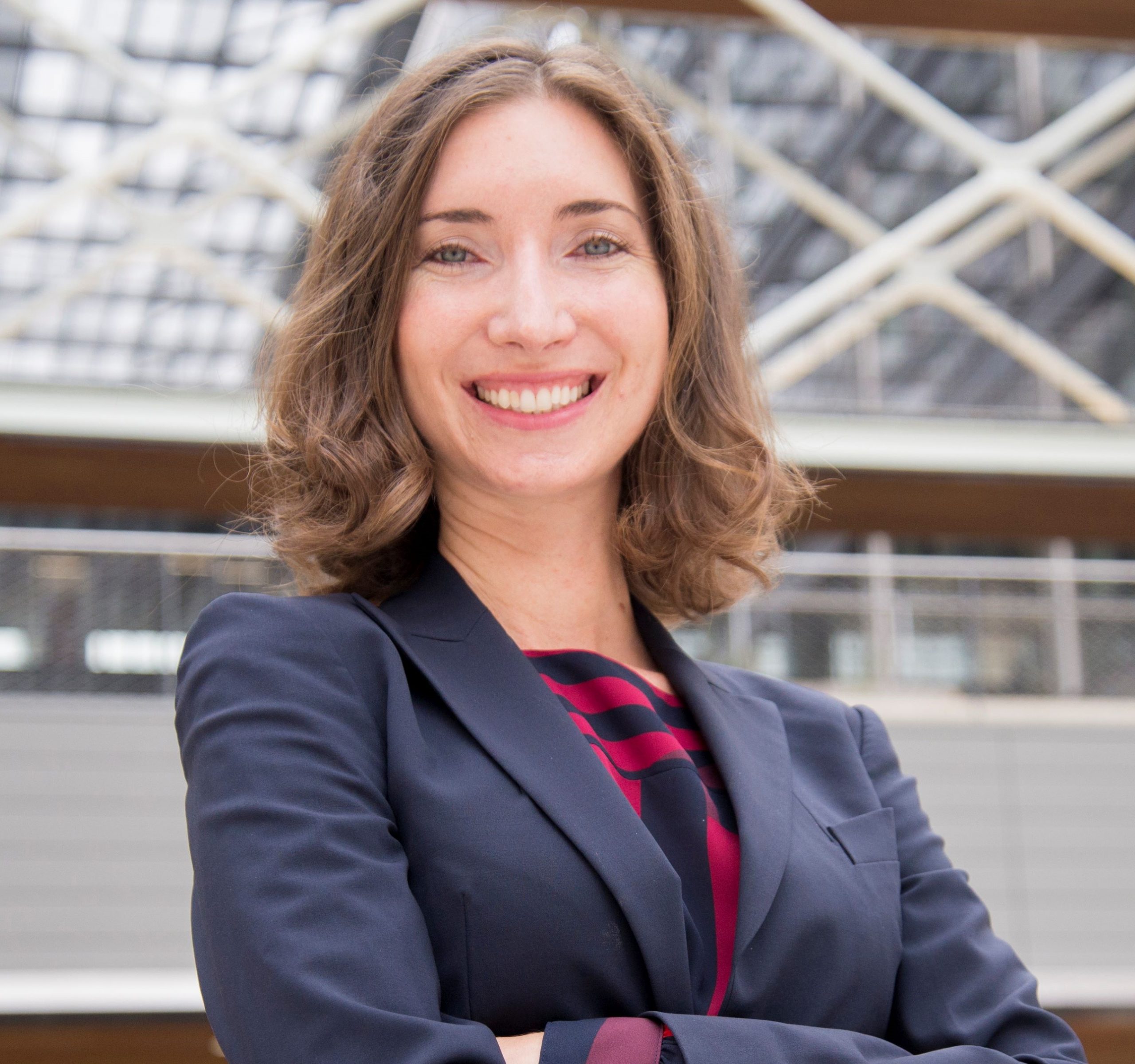 woman with brown hair in navy suit jacket and navy and red blouse standing in research building (photo by Jenny Stein)