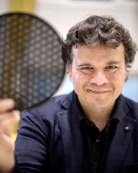 Pablo Jarillo-Herrero holds a translucent black disk comprised of hexagonal cells