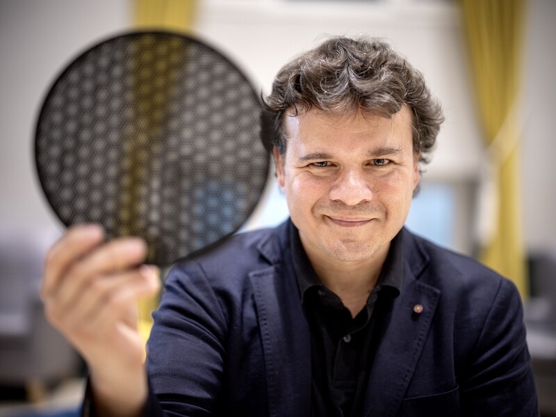 Pablo Jarillo-Herrero holds a translucent black disk comprised of hexagonal cells