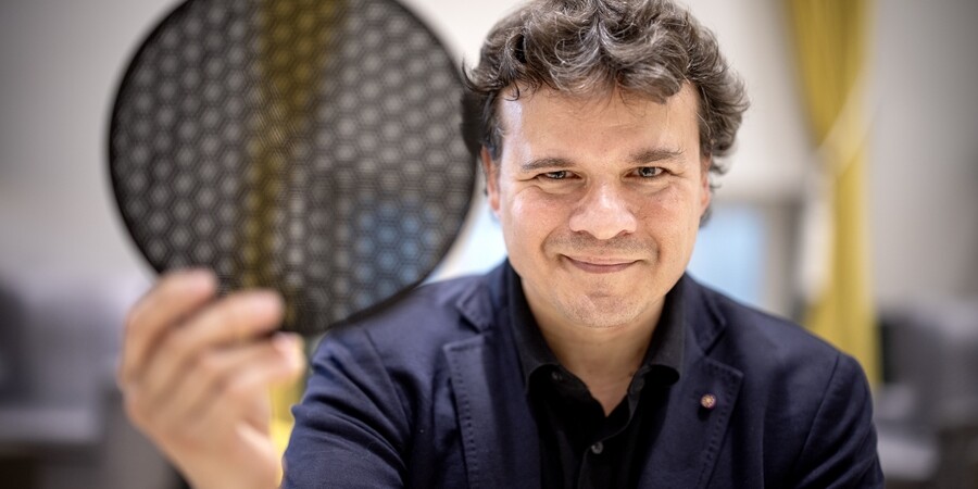 Pablo Jarillo-Herrero holds a translucent black disk comprised of hexagonal cells