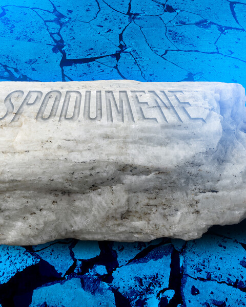 A rock is made of labeled “Spodumene” on blue rocky background.