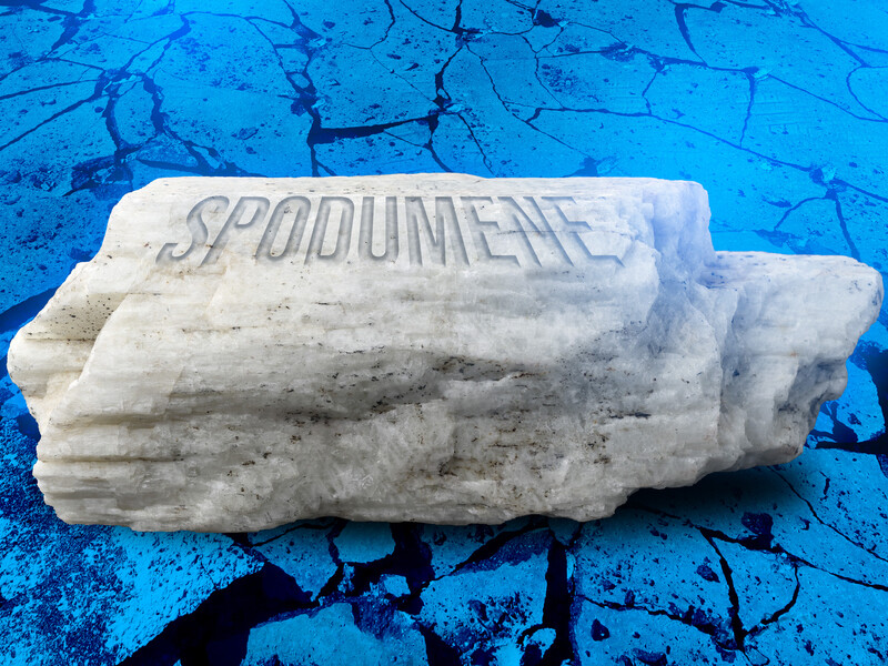 A rock is made of labeled “Spodumene” on blue rocky background.